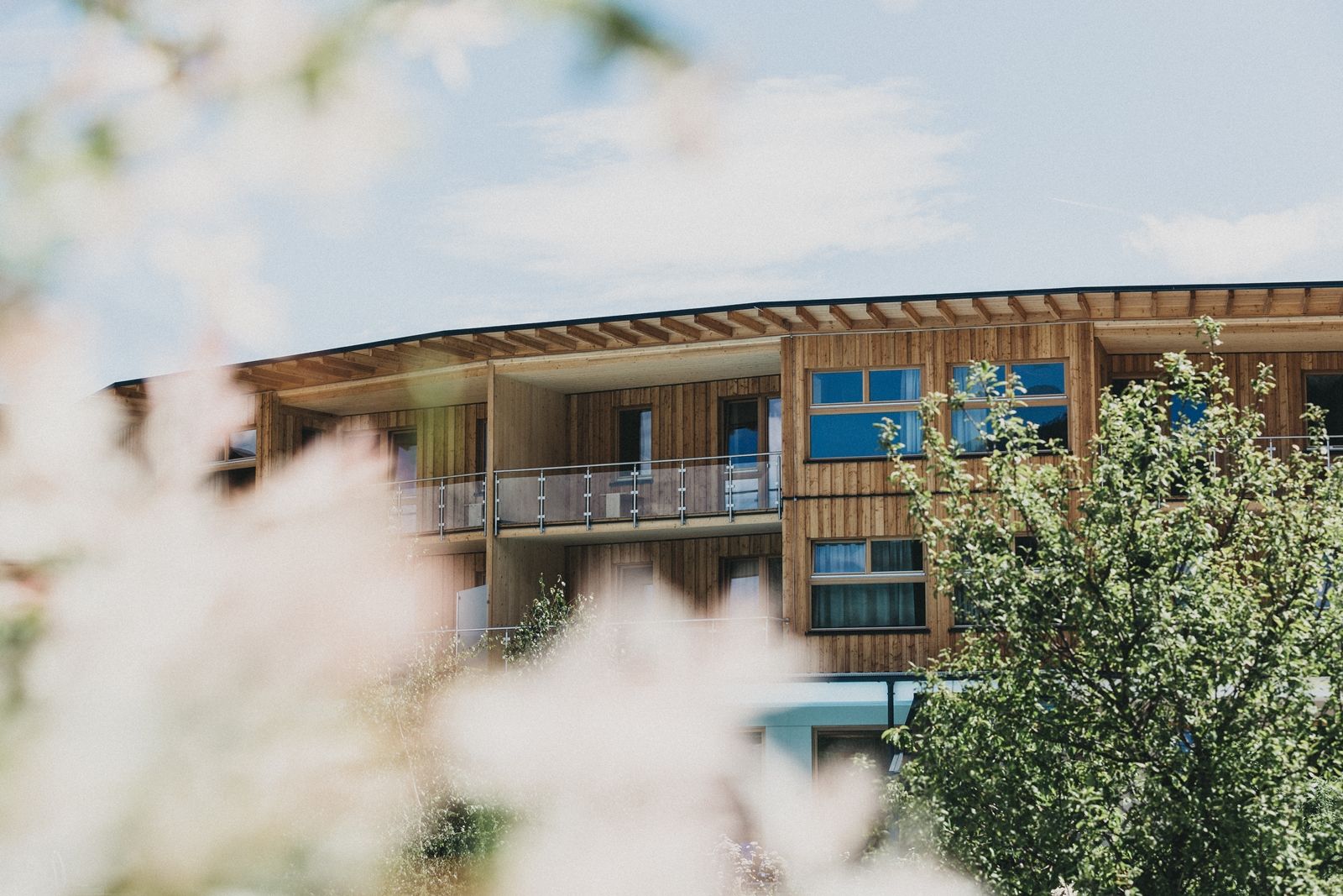 Wooden building of the Naturhotel Molzbachhof with trees in the foreground.