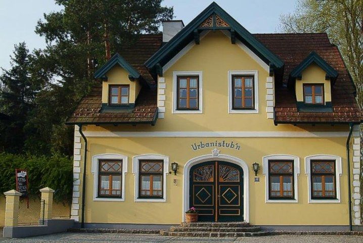 Yellow building with the inscription 'Urbanistubn', surrounded by trees.