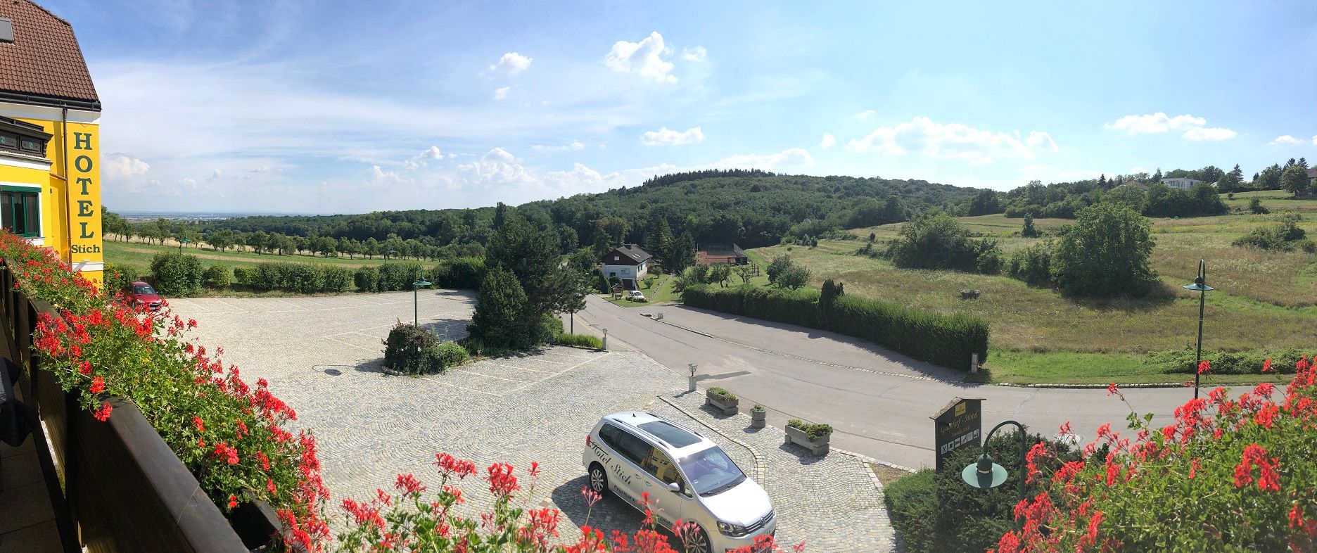 Panoramic view of a rural landscape with hills and meadows from a hotel balcony.