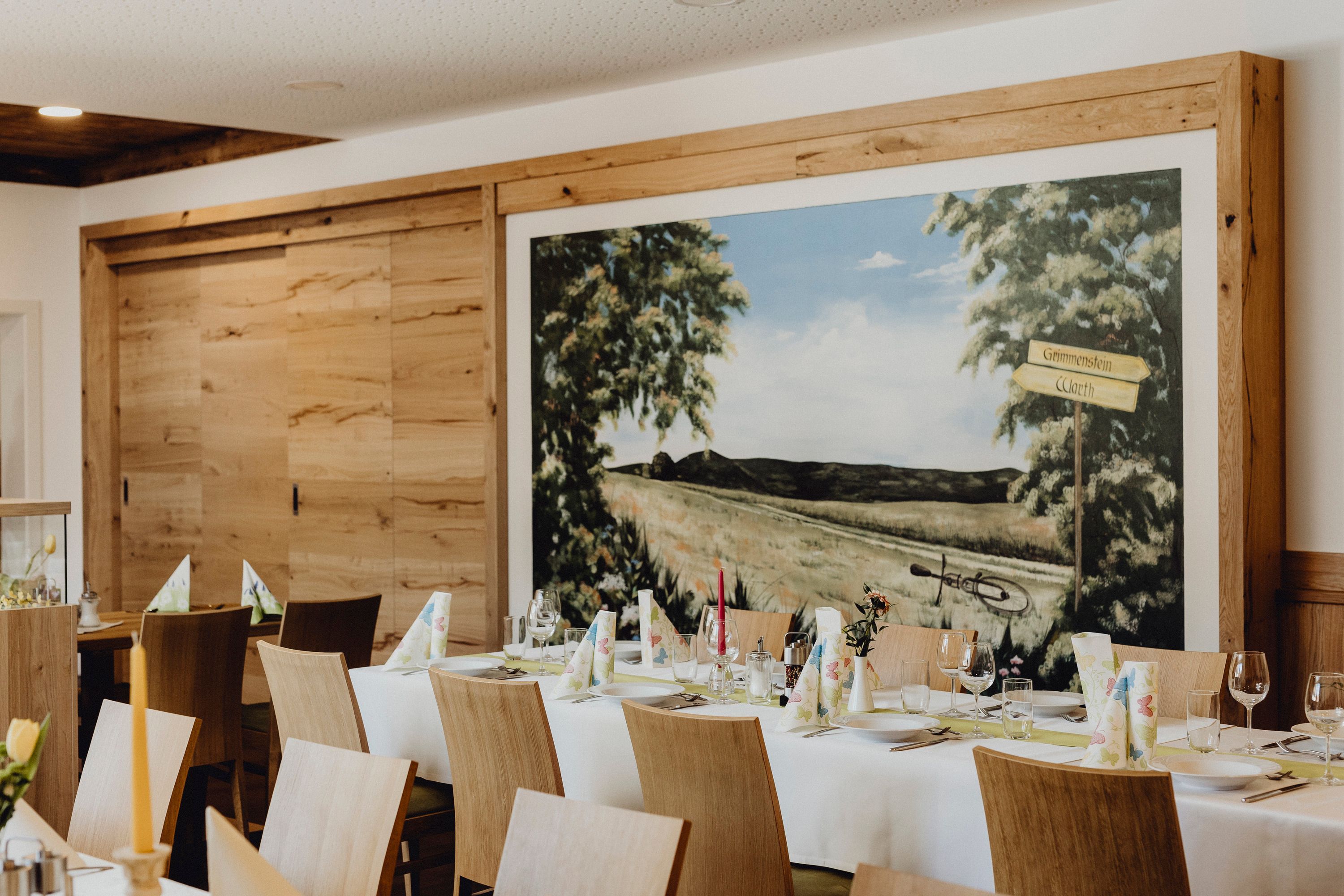 Interior view of an inn with a laid table and wall painting.
