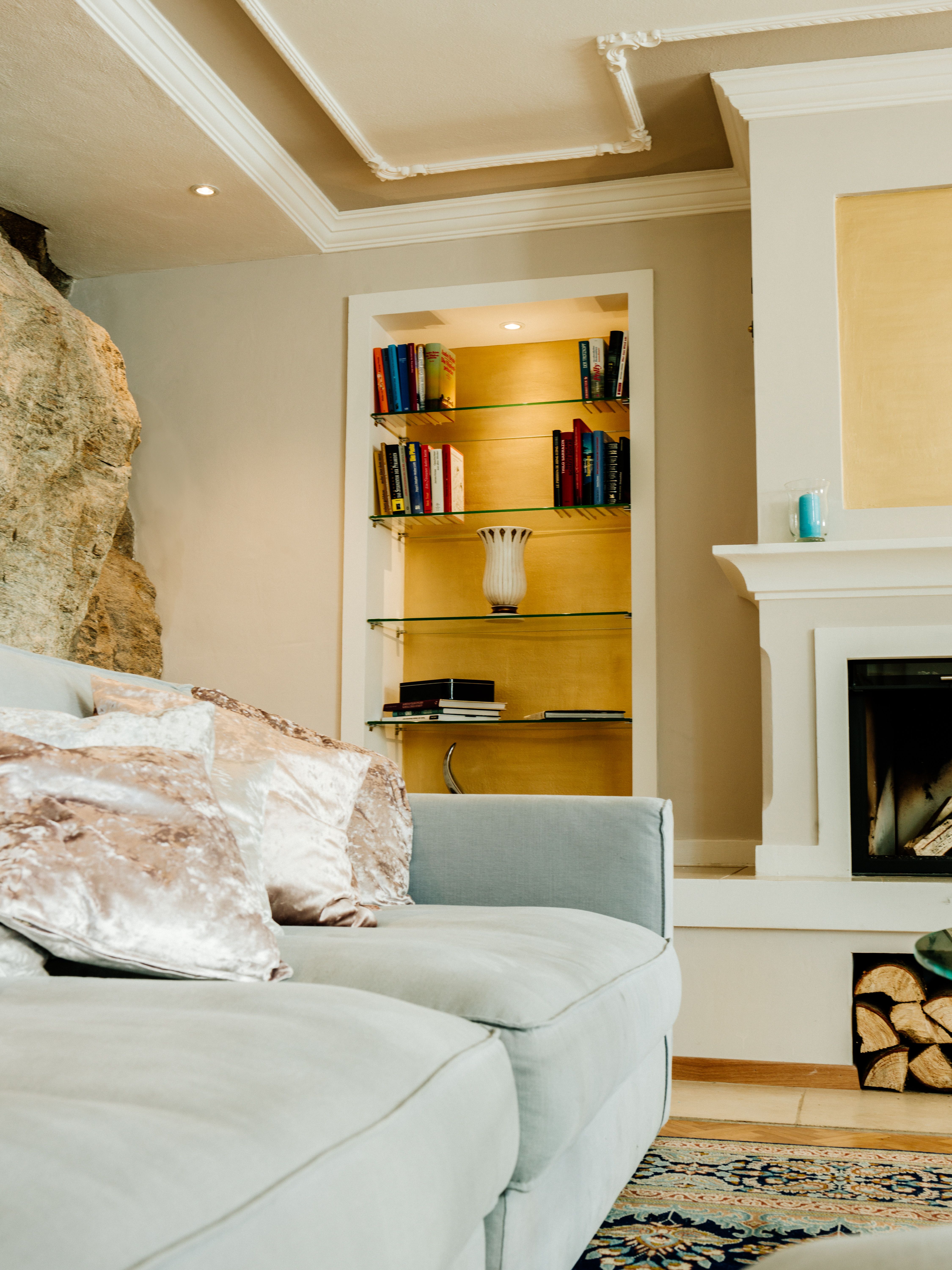 Elegant living room with gray sofa, bookshelf and fireplace.