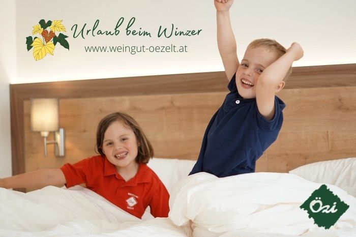 Two children play happily in a bed in a guest room.