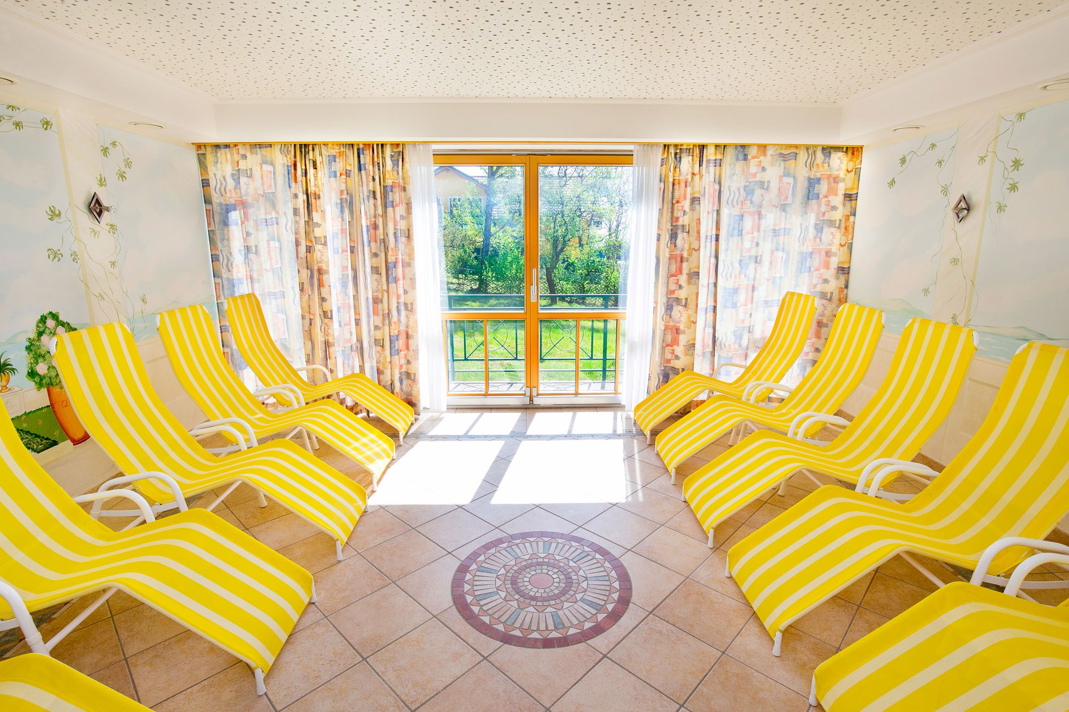 Bright sauna area with yellow and white striped loungers and large windows.