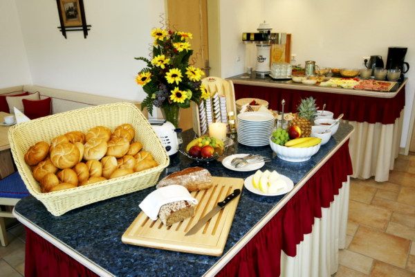 Breakfast buffet with bread rolls, fruit and flowers.