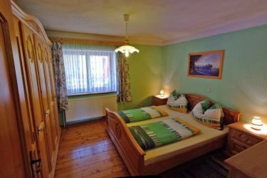 Cozy bedroom with double bed, wooden furniture and green decor.