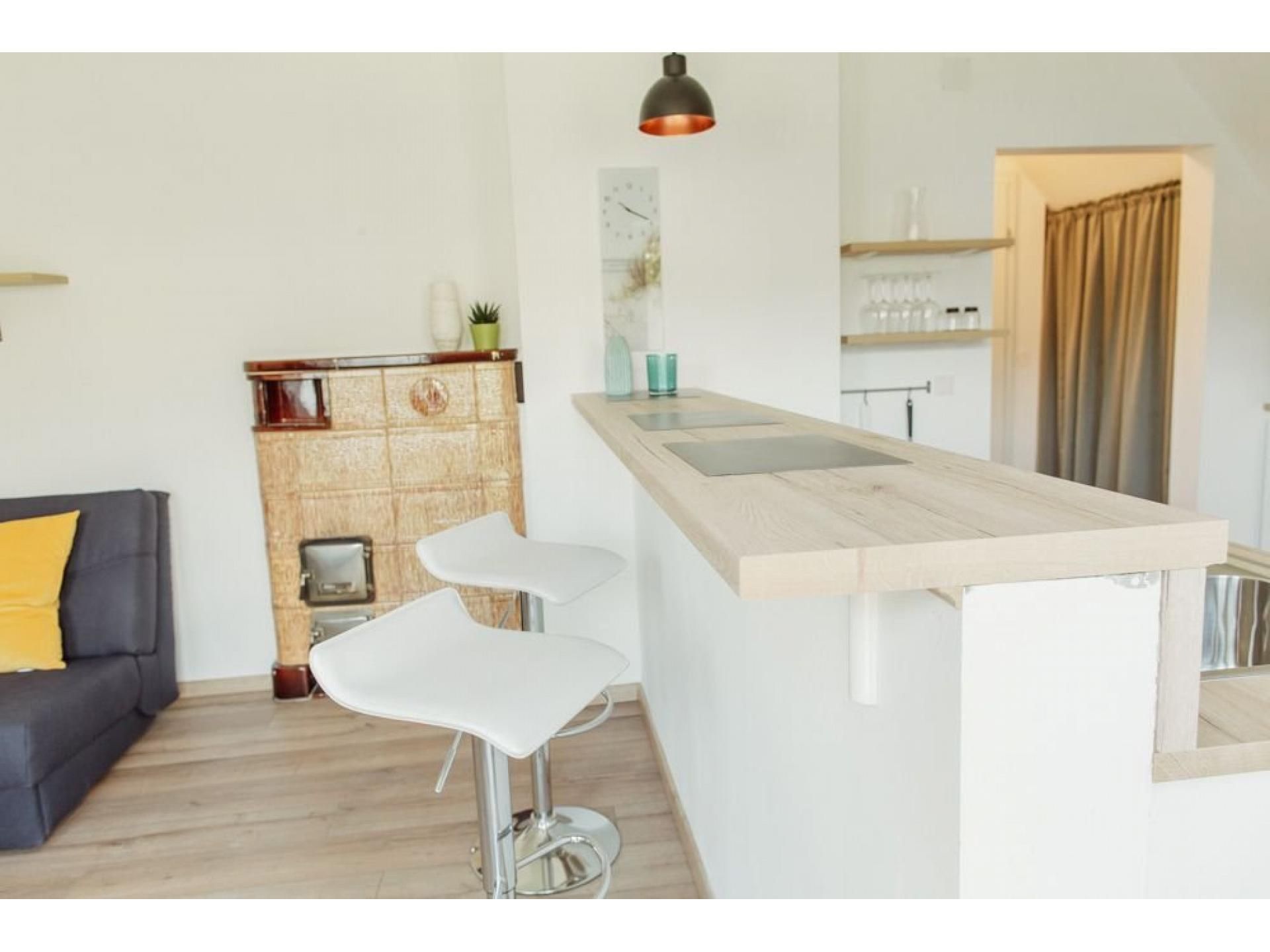Modern kitchen with bar counter, two white bar stools and an old oven.