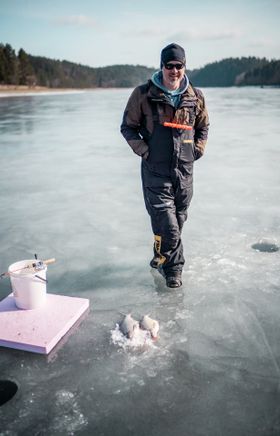 Ein Fischer genießt die Ruhe und die klare Luft beim Eisfischen auf dem gefrorenen Stausee. Die glitzernde Eisfläche und die sanfte Wintersonne schaffen eine friedliche Atmosphäre, die zum Verweilen einlädt. Hier, inmitten der unberührten Natur, wird das Angeln zu einem unvergesslichen Erlebnis.