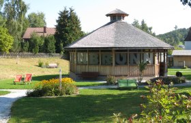 Pavilion in a green park with flowers and deckchairs.