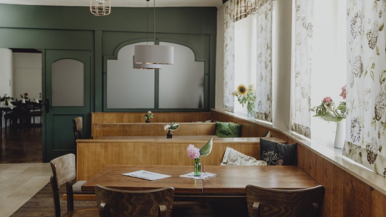 Interior view of a traditional inn with wooden furniture and flowers on the tables.
