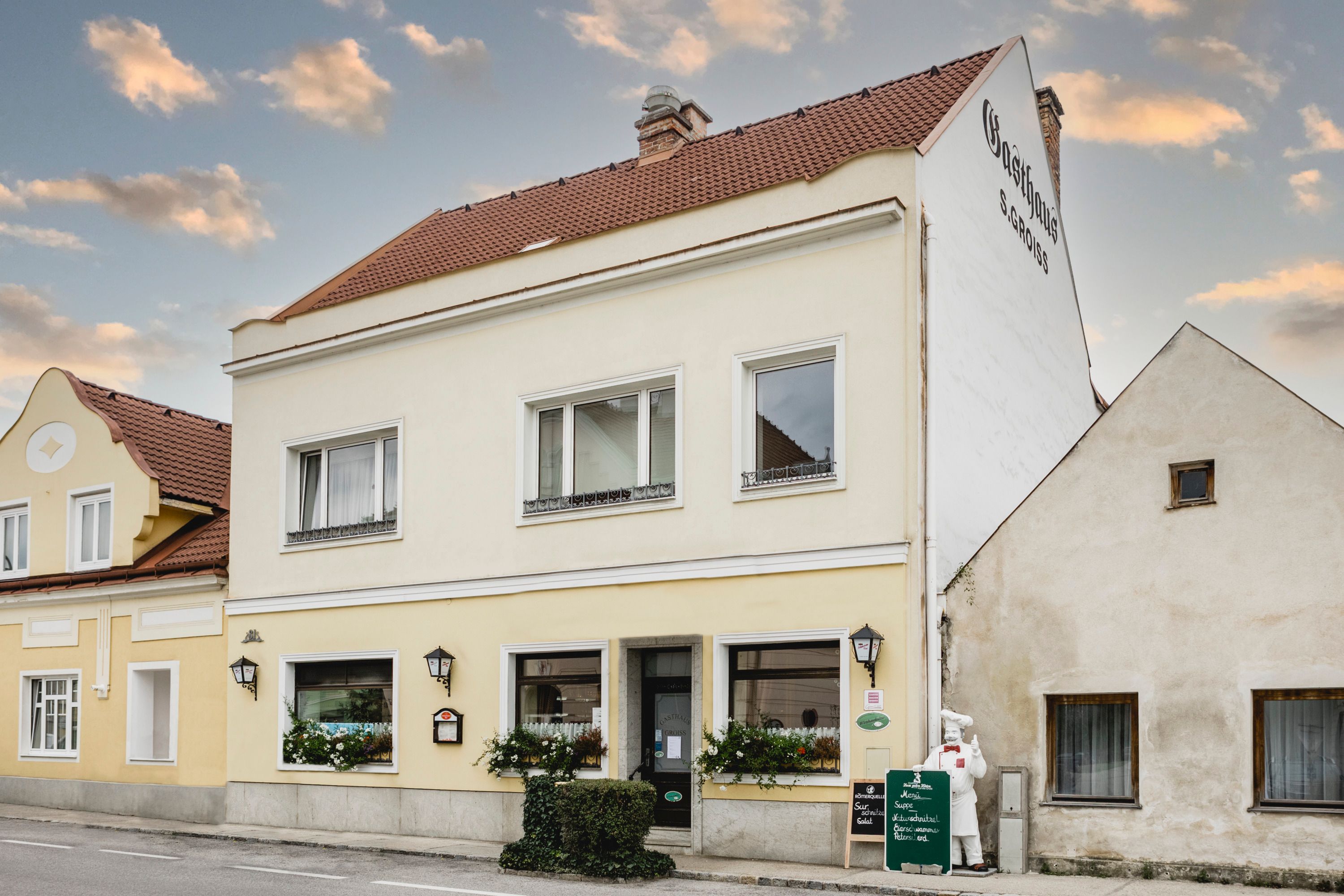 Yellow inn with signs and flowers in Berndorf.
