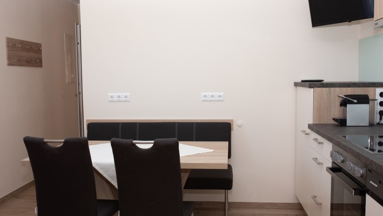 Dining area with table, chairs and kitchenette.