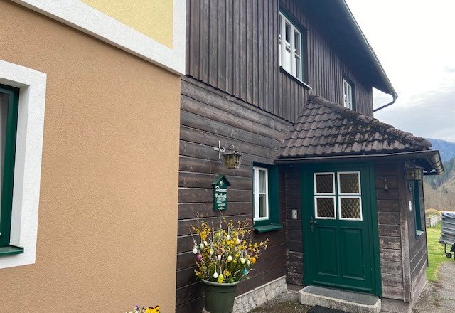 Entrance of a traditional house with wooden paneling and green door frame.