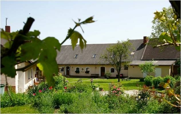 A rural house with a garden and trees in the foreground.