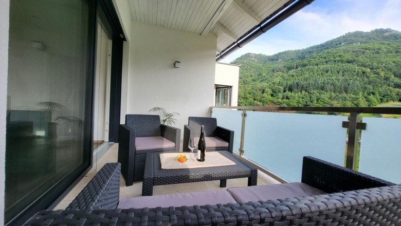 Balcony with rattan furniture and mountain view.