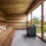 Modern sauna with wood paneling and large glass front with a view of the greenery.