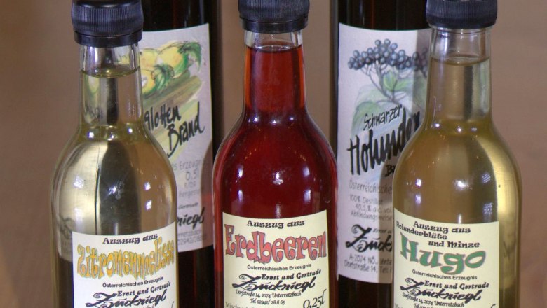 Five bottles of various syrups and schnapps on a wooden table.