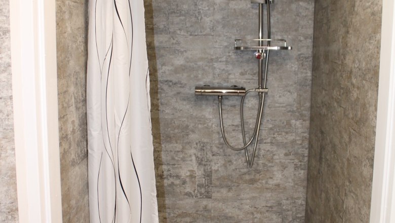 Modern shower with gray tiles and shower curtain.