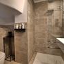 Modern bathroom with gray tiles, shower, washbasin and toilet.