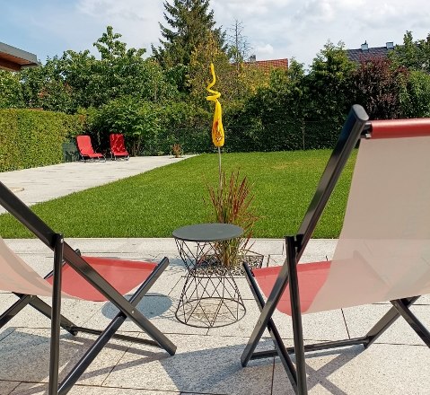 Two sun loungers in the garden with lawn and trees in the background.