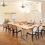 Conference room with tables and chairs, flipchart and chandelier.