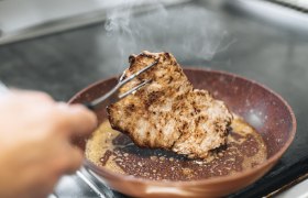 A piece of meat is fried in a pan.