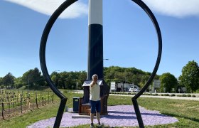 A man stands behind a large key shape in Maissau, with a sign for the Wine Road Weinviertel in the background.