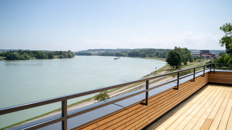 Wooden terrace overlooking a river and green landscape.