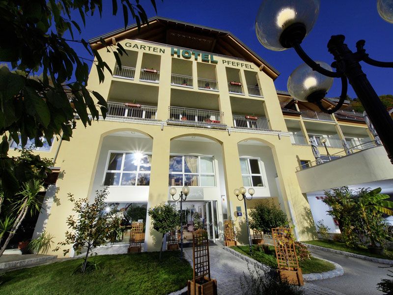 Exterior view of the Gartenhotel Pfeffel with yellow façade and balconies.