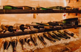 Wine bottles on a shelf on white stones.