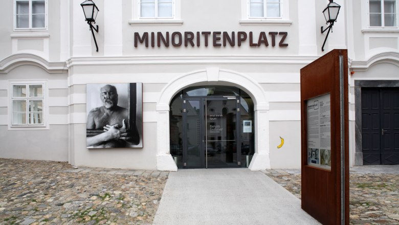Entrance to Forum Frohner on Minoritenplatz with artwork and information board.