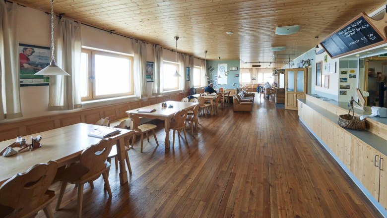Bright dining room with wooden tables, large windows and mountain views.