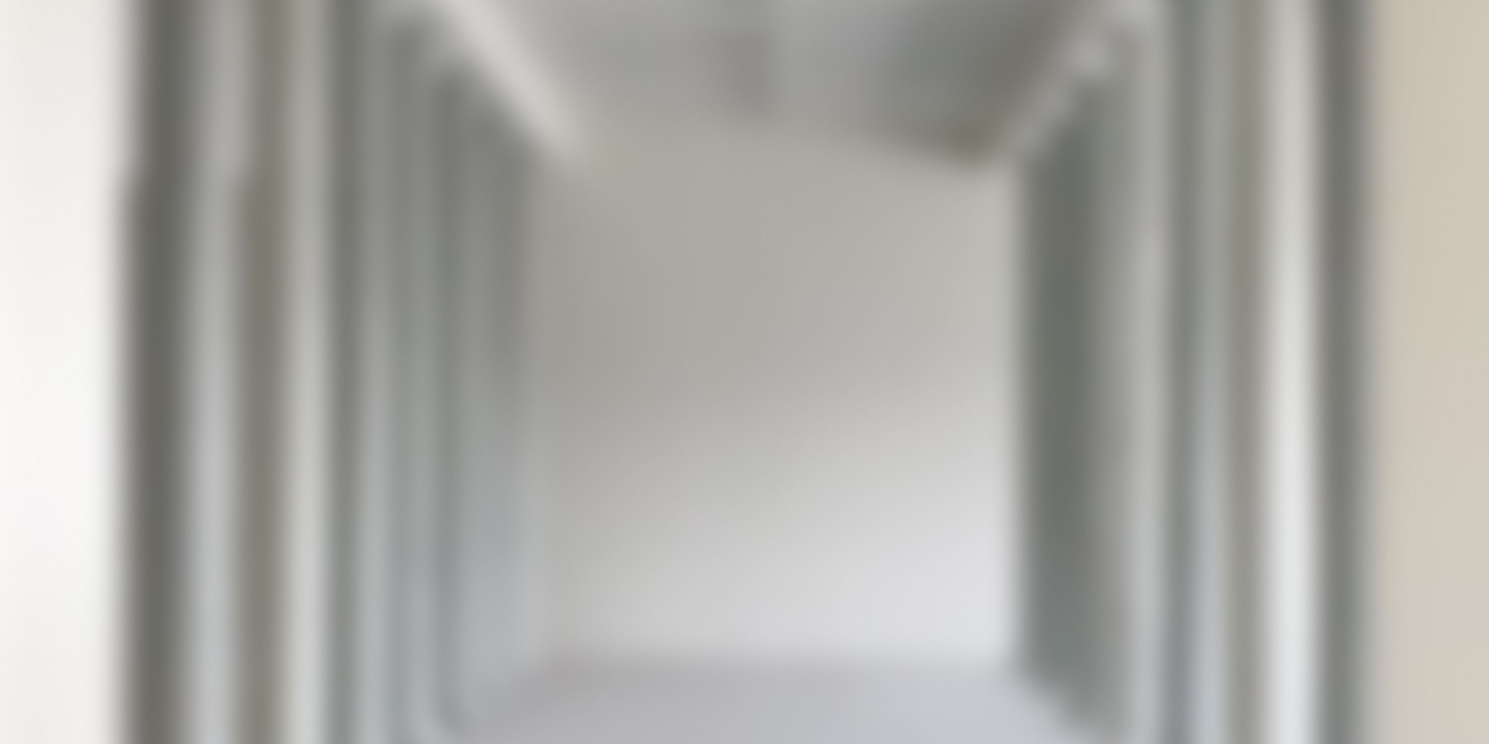 Blurred view into an empty, white room with high ceilings.