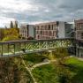 Glass-roofed transition between Therme Laa and hotel building, surrounded by green landscape.