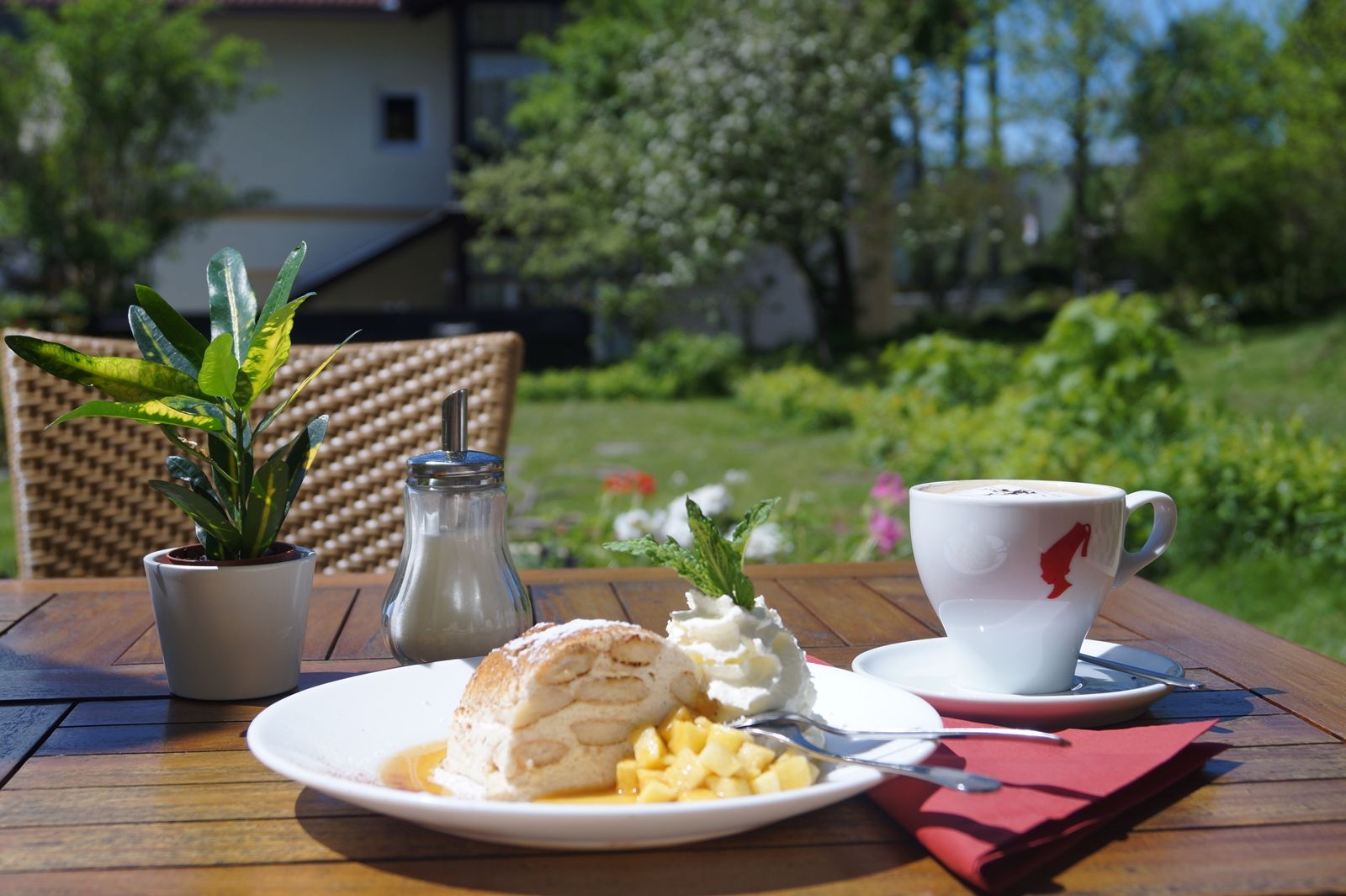 A plate of dessert and a cup of coffee on a table outside.