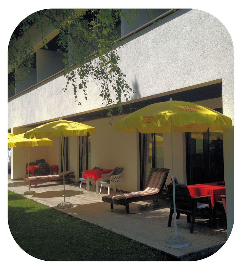 Terrace with yellow parasols and sun loungers in front of a building.