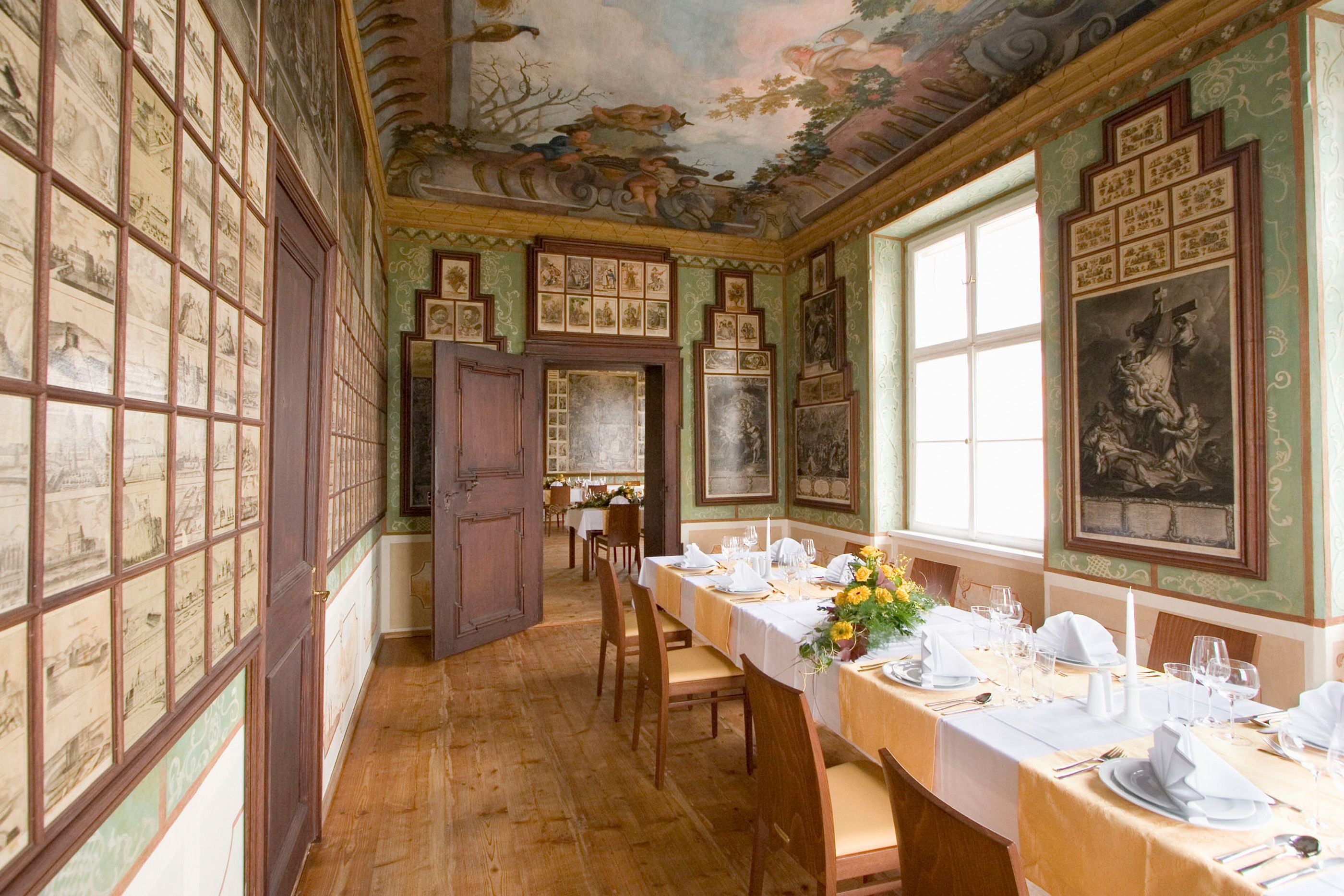 Elegant room with table setting, wall and ceiling paintings.