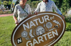 Two people are holding a sign saying 'Nature in the garden'.