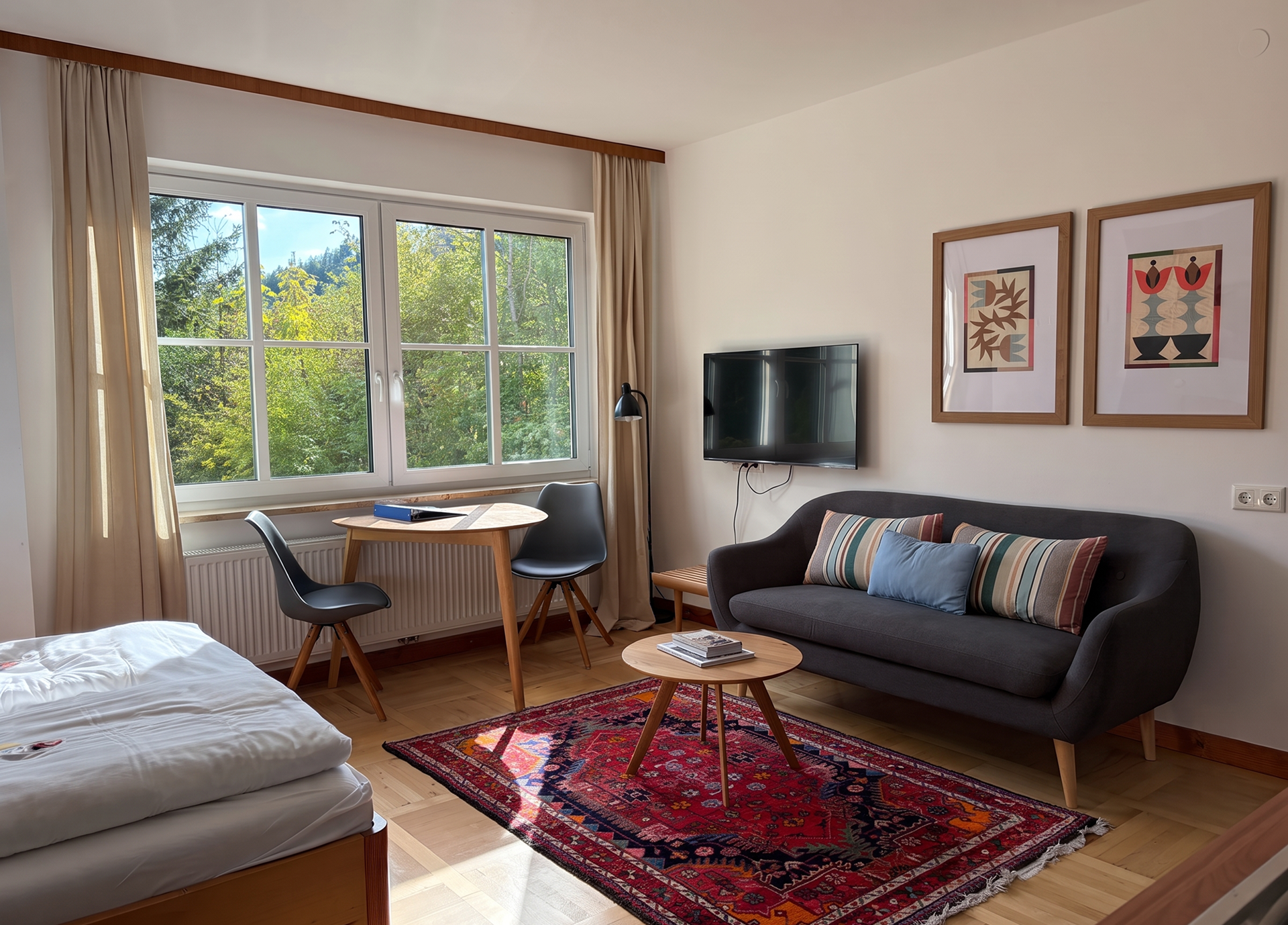 Cozy living room with a sofa, table, chairs, and a large window overlooking the greenery.