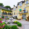 Yellow hotel building with floral decorations and fountain in the foreground.