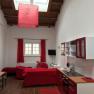 Living and dining area in a loft with red furniture and wooden beamed ceiling.