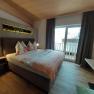 Cozy bedroom with double bed, wooden floor and balcony.