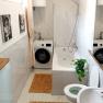 Modern bathroom with bathtub, washing machine and plants.