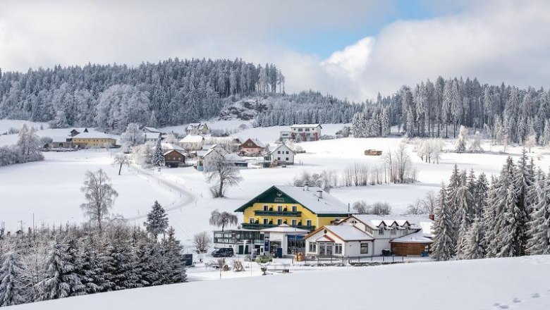 Winter landscape with snow-covered Caf&eacute;-Pension Kristall and surrounding houses.