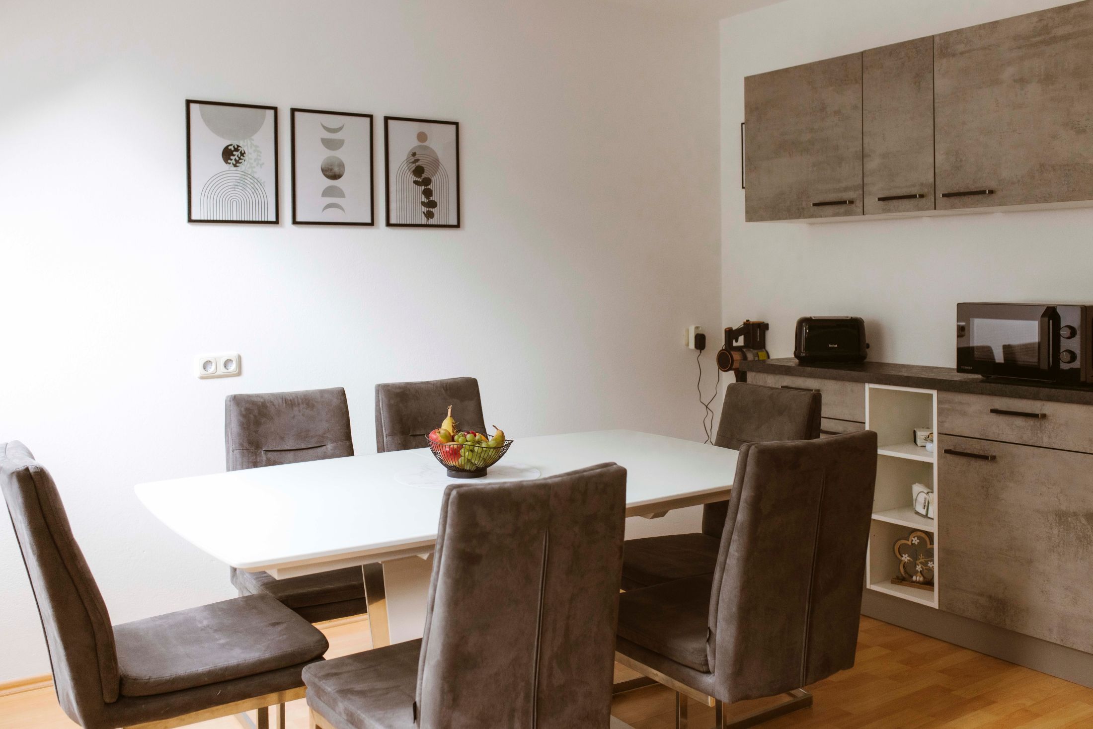 Modern dining area with gray chairs, white table and minimalist decoration.