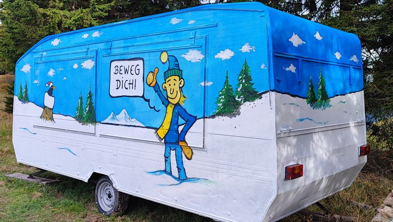 A colorfully painted caravan with a winter landscape and a figure saying "Move!".