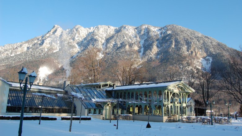 Wintery castle nursery Wartholz in front of a snow-covered mountain.