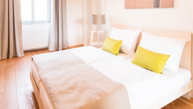 ABOVE, © OBENauf Bright bedroom with double bed, wooden floor and modern lamps.