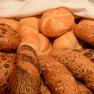 Various types of breakfast pastries, including rolls and baguettes with grains.