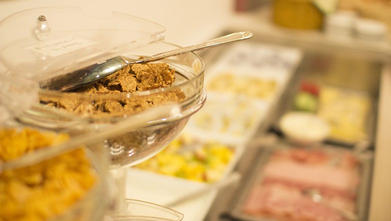 A breakfast buffet with muesli, cold cuts and fruit.