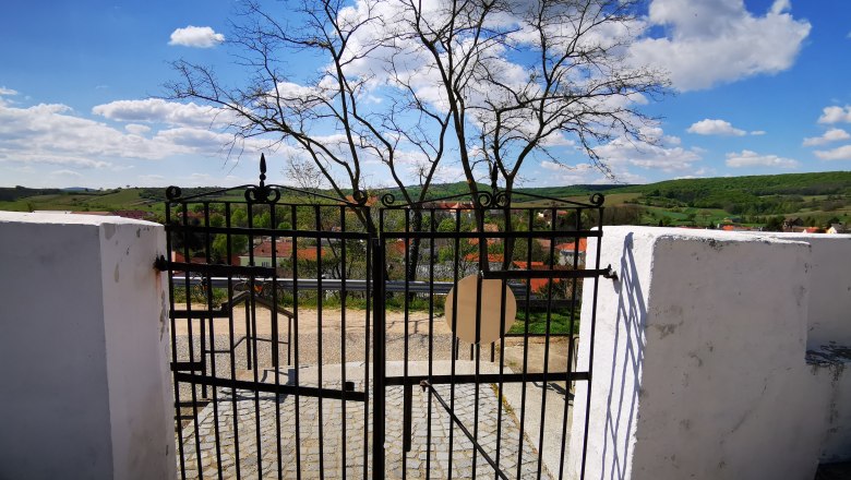 Iron cemetery gate with a view of the countryside and village.